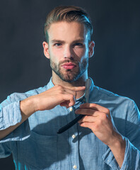 Hairdresser in stylish shirt demonstrating sharp blade of his straight razor for shaving. Tool for barber or shave. Brutal hipster in casual wear with vintage straight razor. Barbershop accessories.