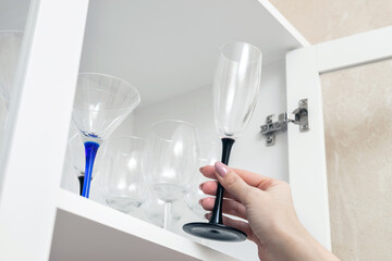 woman takes out a wine glass from the cabinet. martini glass