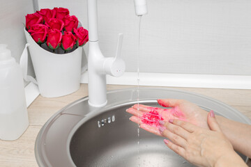 man washes his hands with soap rose petals.
