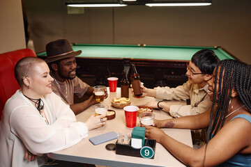 Side view at multiethnic group of adults enjoying time together at diner table