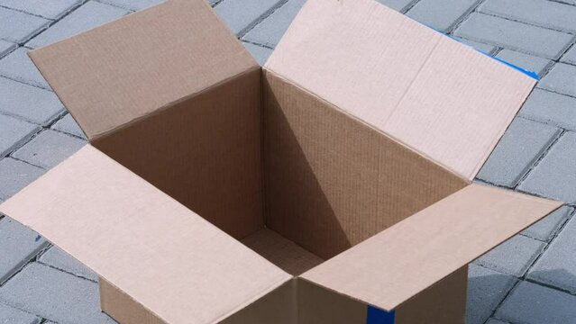 An empty cardboard box lying on tiles outside. Close up.