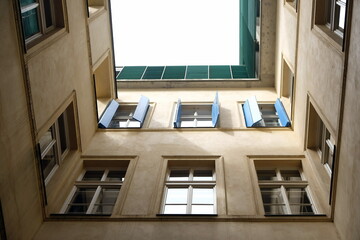 Schöner Altbau in Khaki und Naturfarben mit Fensterläden in Blau in ein einem engen Hinterhof in der Altstadt von Prag in Tschechien - obrazy, fototapety, plakaty