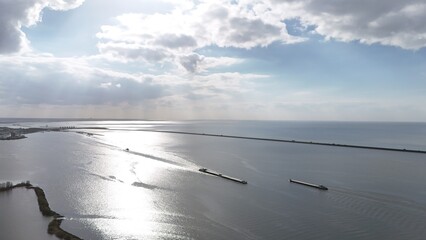 Aerial view of a serene waterway with barges, featuring sunbeams piercing through clouds,...