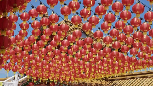Many red traditional Chinese Lantern lamps blowing in the wind next to a temple in Kuala Lumpur, Malaysia