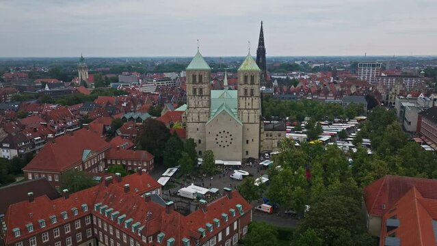 An aerial drone shot of St. Paulus Dom, also known as M&uuml;nster Cathedral, on Domplatz in M&uuml;nster on a sunny day. It is a central and culturally significant area of central M&uuml;nster, Germany. Busy Market