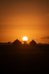 Sunset in the countryside with silhouette of wooden huts