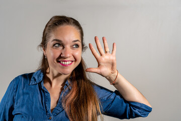 Mujer haciendo el numero 5 con la palma de su mano. Mujer saludando. Fotografía de estudio	