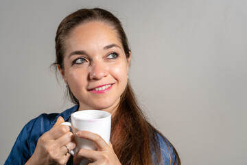 Mujer sonriente tomando cafe mientras piensa una idea agradable