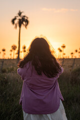 woman looking at the sunset with palm trees in the background