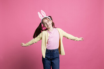 Happy schoolgirl with pigtails and bunny ears dancing in studio, showing modern lovely dance moves in front of camera. Young child celebrating easter holiday festivity, carefree junior.