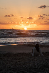 Woman on the beach contemplating the sunrise