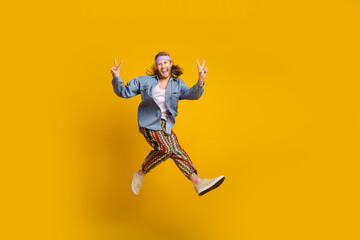 Fototapeta na wymiar Full body portrait of cool young man jump show v-sign empty space wear denim shirt isolated on yellow color background