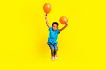 Full body photo of little beautiful child dressed blue t-shirt jeans flying with helium bubbles...