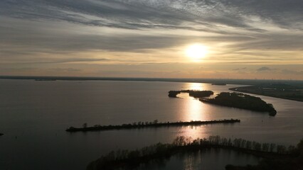 Scenic aerial view of a tranquil lake at sunset with islands and peninsulas, silhouetted against...