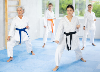 Female students of martial arts academy look at Kata karate teacher conducts classes and performs movements and fighting techniques together