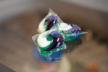 Laundry detergent soap pods sit on top of a washing machine.