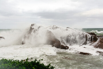 Immense waves hitting a large rock at the edge of the beach. Force of nature.
