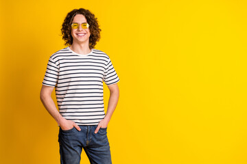 Photo of nice young man posing empty space wear striped t-shirt isolated on yellow color background