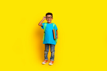 Full length photo of sweet excited preteen boy wear blue t-shirt spectacles walking school empty space isolated yellow color background - obrazy, fototapety, plakaty