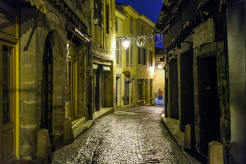 Fototapeta na wymiar A narrow alley illuminated at night in the La Cite' old town inside the medieval walls of the castle in the historic city of Carcassonne, France.