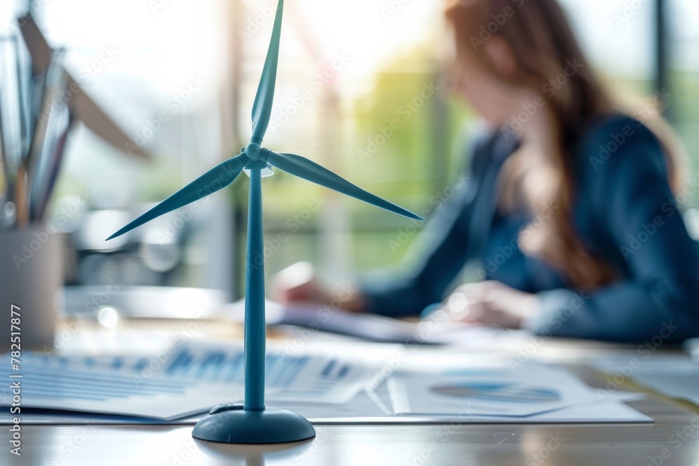 Poster a small wind turbine model stands prominently on a desk strewn with graphs and reports, symbolizing 