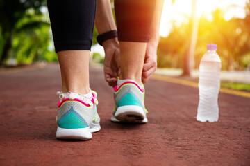 Runner woman tying up laces of shoes, getting ready to run for cardio and weight loss