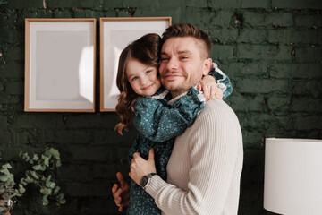 Happy Father's Day. Smiling young dad embraces with big hug his adorable little child daughter at...