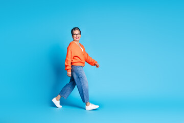 Fototapeta premium Full body photo of lovely senior lady walking shopping dressed stylish orange garment isolated on blue color background
