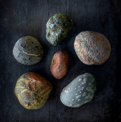 Six rocks on slate surface and light-painted from the side. - obrazy, fototapety, plakaty