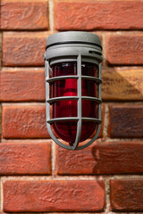 Red emergency lamp on a brick wall
