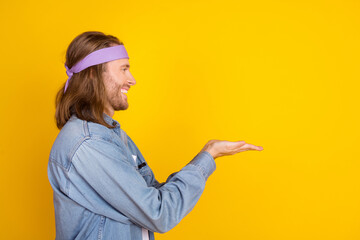 Photo portrait of attractive young hippie man profile palms hold empty space wear trendy denim...