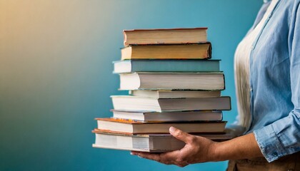 Woman hands holding pile of books over light blue background. Education, library, science, knowledge, studies, book swap, hobby, relax time
