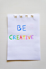 A Piece Of Paper That Says Be Creative near a notepad