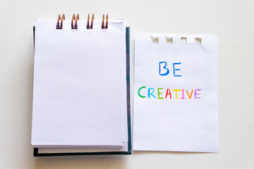 A Piece Of Paper That Says Be Creative near a notepad