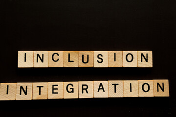 Wooden Blocks Spelling Out Inclusion and Integration on a Dark Surface
