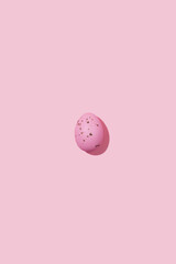 One pink speckled Easter egg casting shadow on pink background, minimalism concept, copy space
