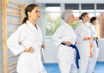 Female students of martial arts academy look at Kata karate teacher conducts classes and performs movements and fighting techniques together