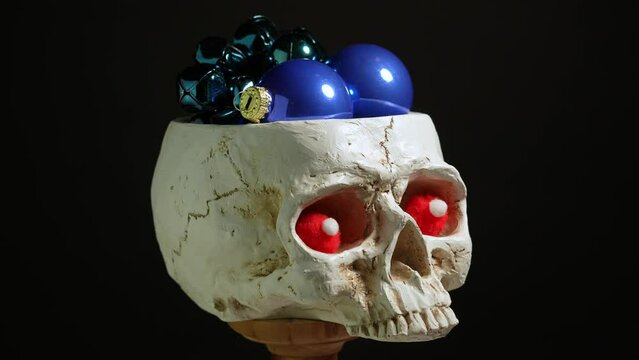 Gothic human skull with Christmas balls toys. Dark moody gothic Christmas celebration. Human head skull dark concept.