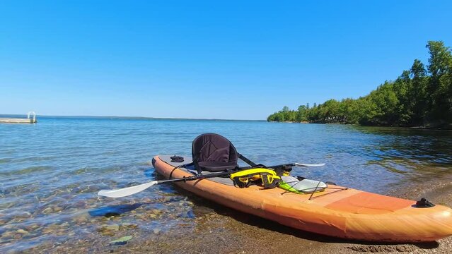 View of paddle board with sport equipment, outdoor activities, yellow waterproof bag, oar rowing on calm great lake water. Water sport and leisure hobby tools. Traveling and adventure in Canada.