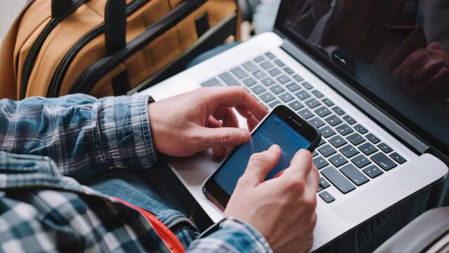 Man using a laptop and smartphone for tour reservation or booking online.