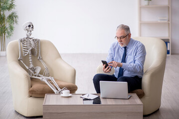 Old male psychologist meeting with skeleton - 782569259