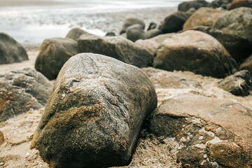 Stone groyne on beach background.Stone boulders on the beach at low tide.Marine photo wallpaper.Nature of the North Sea coast. Frisian Islands of Germany. Rest on the sea. 