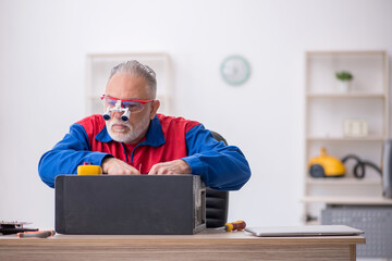 Old male repairman repairing computer