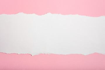 White paper torn on both sides on pink paper background. Blank space for text.