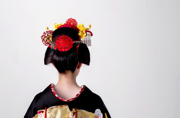 A Japanese woman is having her hair styled into a traditional bun, with flowers and other decorative elements on top. For special occasions, she wears an elegant kimono. - 782576075