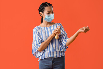 Young Asian woman in medical mask and with mosquito repellent on orange background