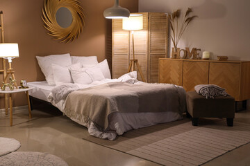Interior of bedroom with blankets and glowing lamps in evening