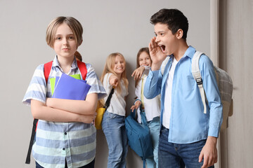 Bullied little boy with copybooks and his classmates at school - obrazy, fototapety, plakaty
