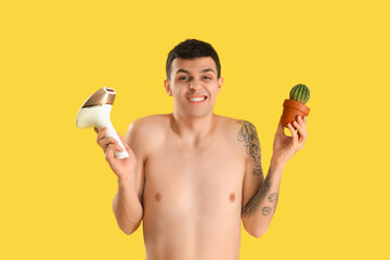 Emotional young man with photoepilator and cactus on yellow background