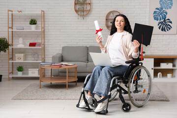 Beautiful female student in wheelchair with graduation cap, diploma and modern laptop at home